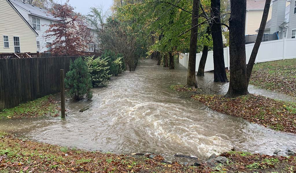 Flooding between fenced in backyards in residential neighborhood.