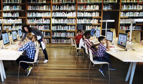 Children sitting at computers in a library.