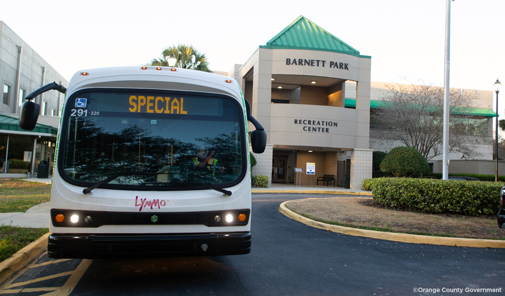 A bus is parked outside a neighborhood center named Barnett Park Recreation Center at the entrance