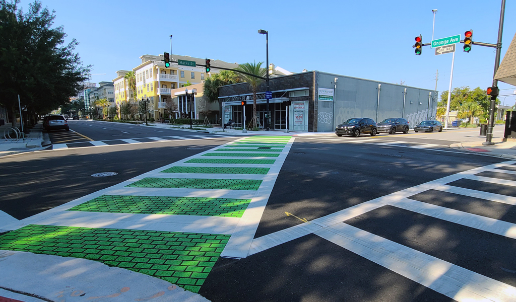 A bicycle crosswalk is painted bright green across a busy intersection