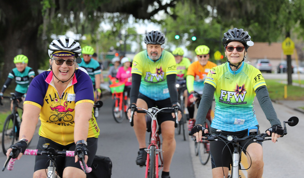 Colorfully dressed people ride bikes through a neighborhood.