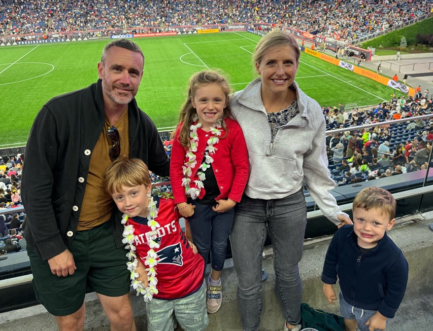A family with young children smiling at a football game.