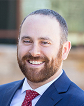 Aaron Guyette in a blue blazer, white shirt and red tie