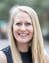 Ales DeYoung smiling in a navy blue dress.