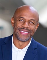 Bill Anderson smiling in a navy blue blazer and white shirt.