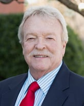 Bob Taliaferro smiles at the camera wearing a red tie. 