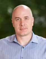 Chris Danforth smiling outside in a striped shirt.