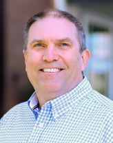 Chris Wilson smiling in a blue checkered shirt.