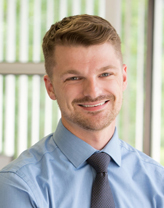 Dan Schandel in a blue collared shirt a blue tie with white dots.