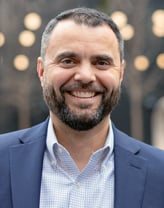 David smiling in a navy-blue blazer.