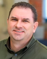 Don wearing a green button down shirt in an office setting.