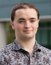 Drew Racz smiling in a floral shirt.