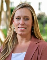 Laura Wood smiling outside in a pink blazer.