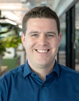 Matthew Kalish smiling in the office in a blue shirt.