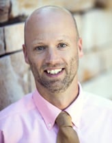 Ryan Cloutier smiling in a magenta shirt and brown tie.