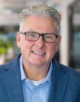 Sean Manning smiling in a checkered blazer.