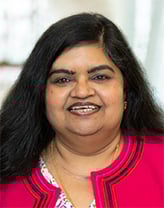 Taruna smiling in a navy blue blouse.