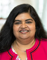 Taruna smiling in a navy blue blouse.