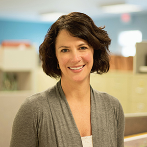 Jennifer smiling amongst office cubicles.