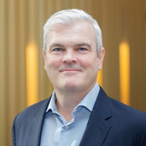 Ryan McManus smiling in a suit.