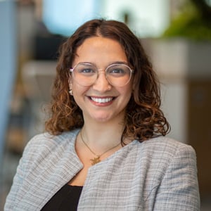 Sara Yasmin smiling in a gray blazer and black shirt.