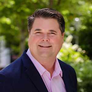 Wayne Robinson in a pink shirt and navy blue jacket.