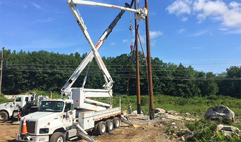 A power truck installs new electric power poles.