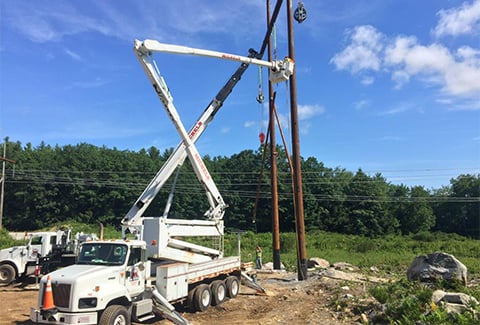 A power truck installs new electric power poles.