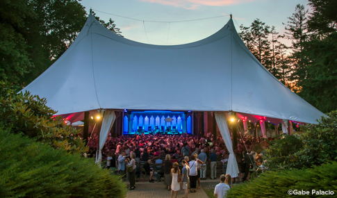 People gathered for outdoor evening tented theater performance at Caramoor Center.