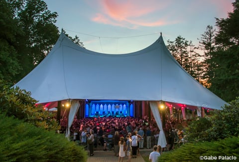 People gathered for outdoor evening tented theater performance at Caramoor Center.