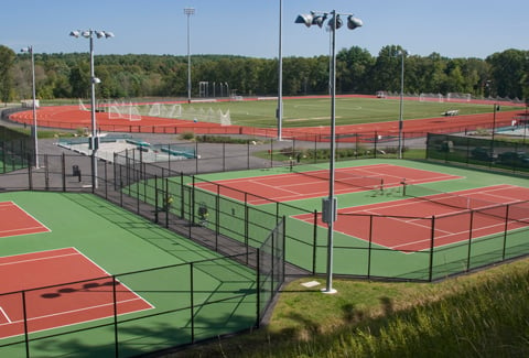 The Regis College tennis courts with the soccer field and surrounding track located in the background.