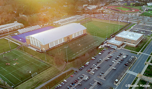 The sun setting over the University of Virginia’s Welsh Indoor Practice Field complex, practice fields, and parking lot.  