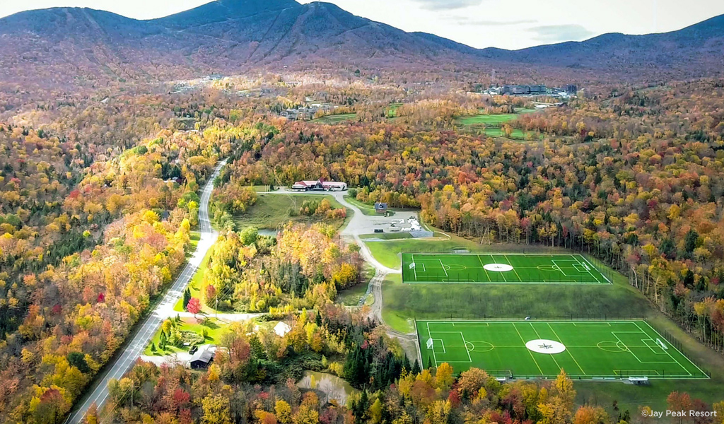 Aerial view of two athletic fields with a fall mountain backdrop