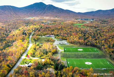 Aerial view of two athletic fields with a fall mountain backdrop