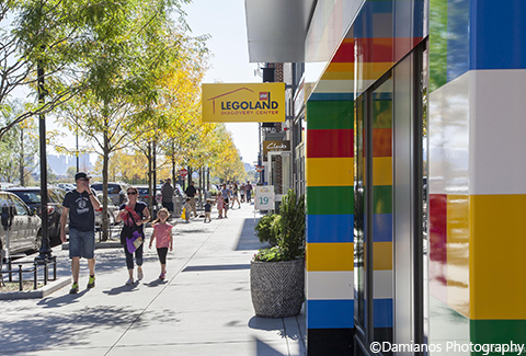 Visitors walk along the sidewalk near the Lego store at Assembly Row.