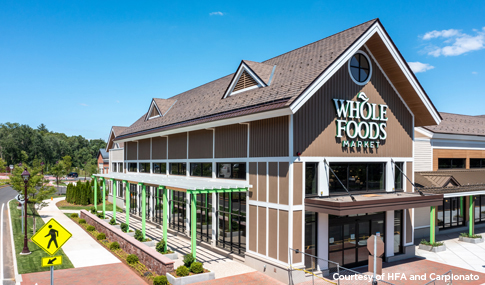 Close-up of Whole Foods Market exterior entrance with brick papers, green landscaping, and sidewalks.
