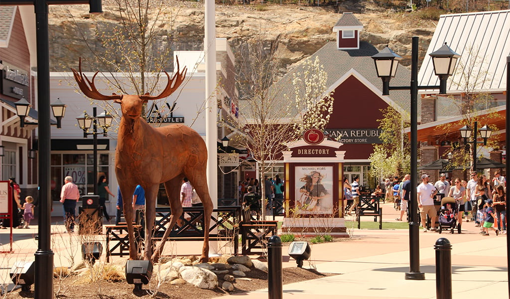 A moose statue stands is surrounded by several shops at the entrance of Merrimack Premium Outlets.