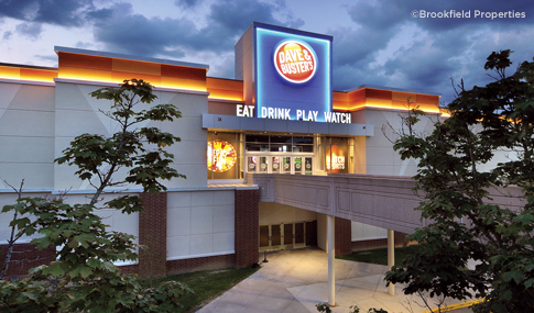 Nighttime exterior view of entrance to Dave & Buster’s with orange and blue illuminated logo.