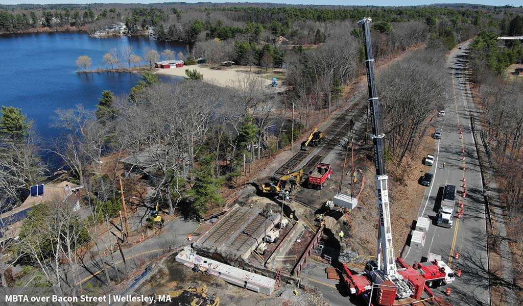 Aerial view of bridge rail replacement with construction workers and equipment.