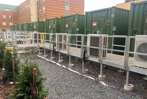 Green industrial battery containers arranged in a row.