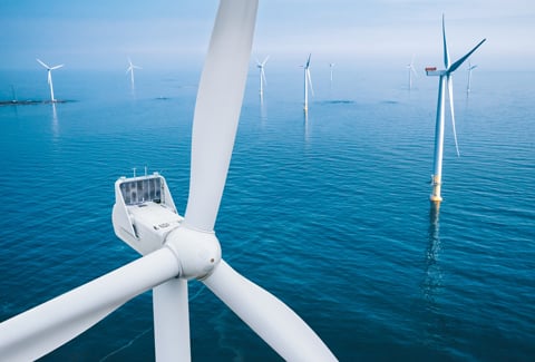 Aerial view of wind turbines or windmills farm field in blue sea