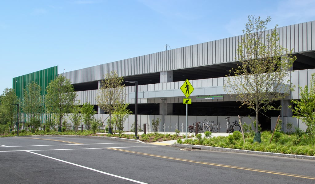 Entrance view of new parking garage with modern facade treatment and vehicle access road with pedestrian crossing in the foreground.