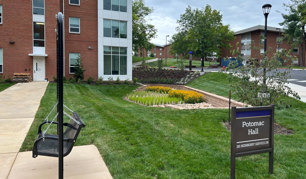 2-	Potomac Hall sign in front of the new building with a black swinging bench.
