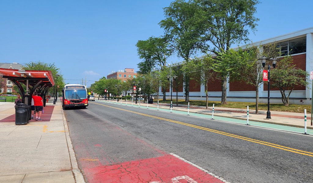 Rutgers bus stopping on a two-way campus street with a bike lane across the road.