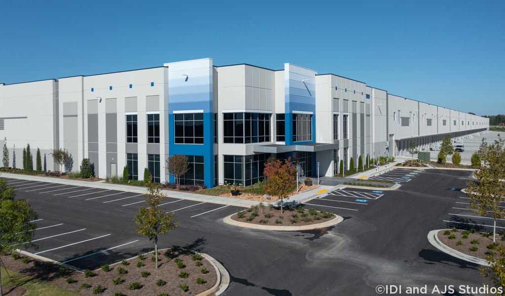 Front entry of an industrial logistics facility depicting parking field and loading docks.