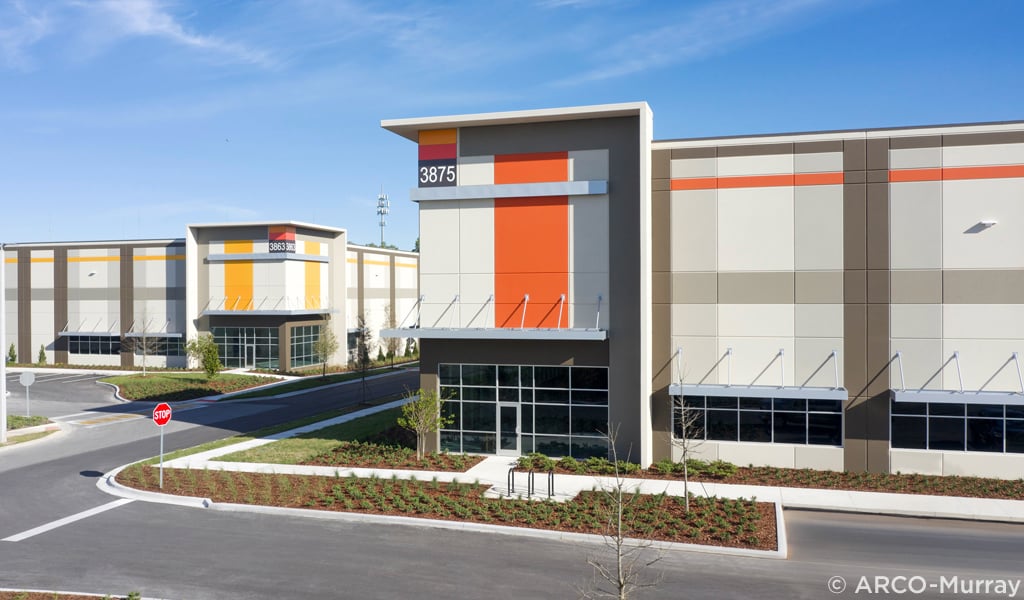 Exterior view of two large industrial buildings under a clear blue sky.