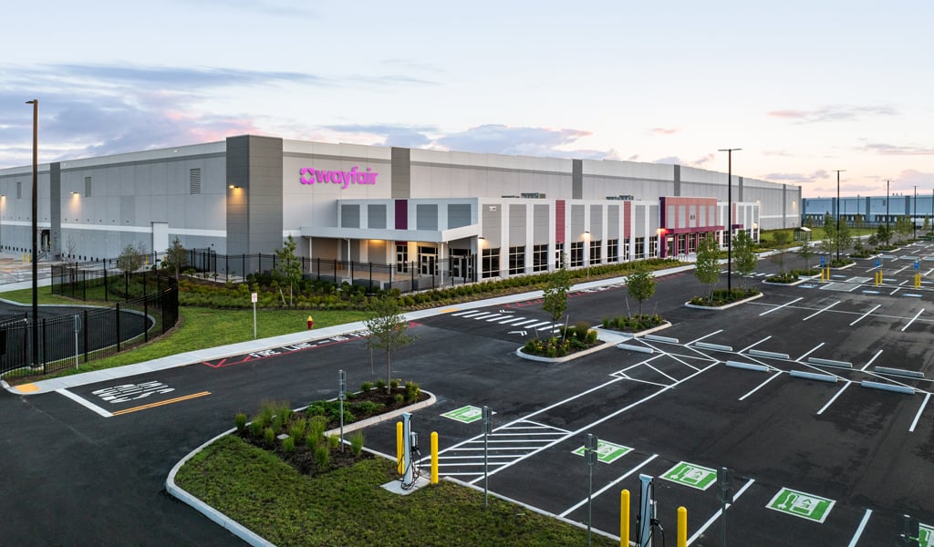 A Wayfair logistics center with parking lot featuring EV charging stations.