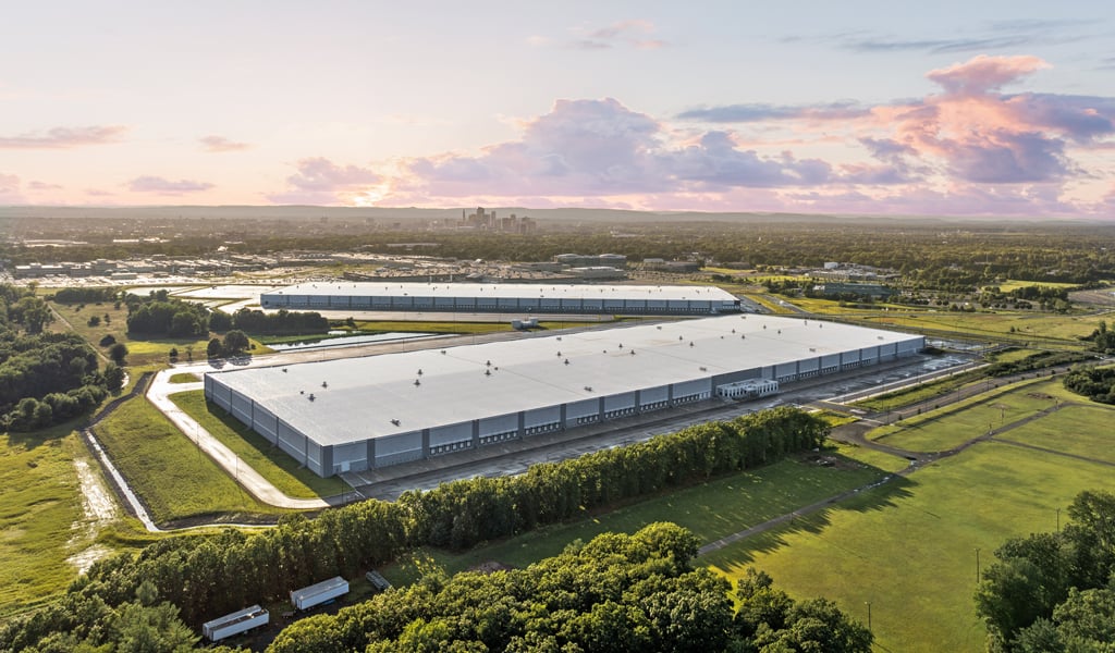 An overhead view of an industrial warehouse with a city in the background.