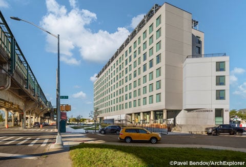 Street-level view of Beach Green Dunes III with elevated A train platform above Rockaway Freeway to the left.