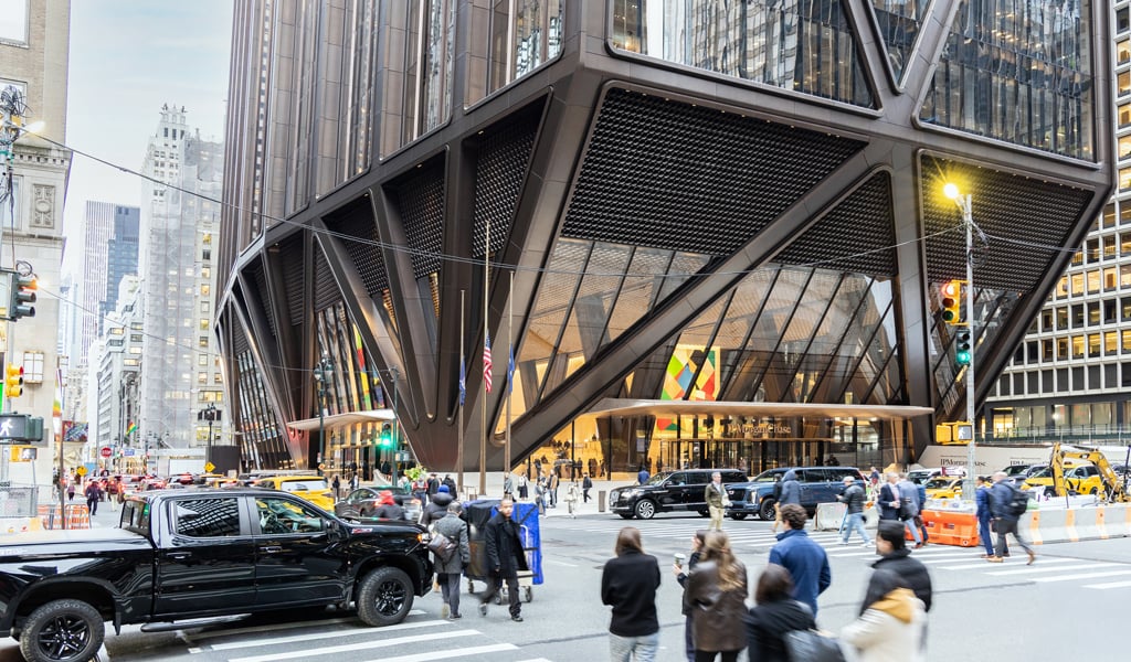 Pedestrians and vehicles at a busy city intersection in front of the JPMorgan Chase’s modern headquarters in New York City. 